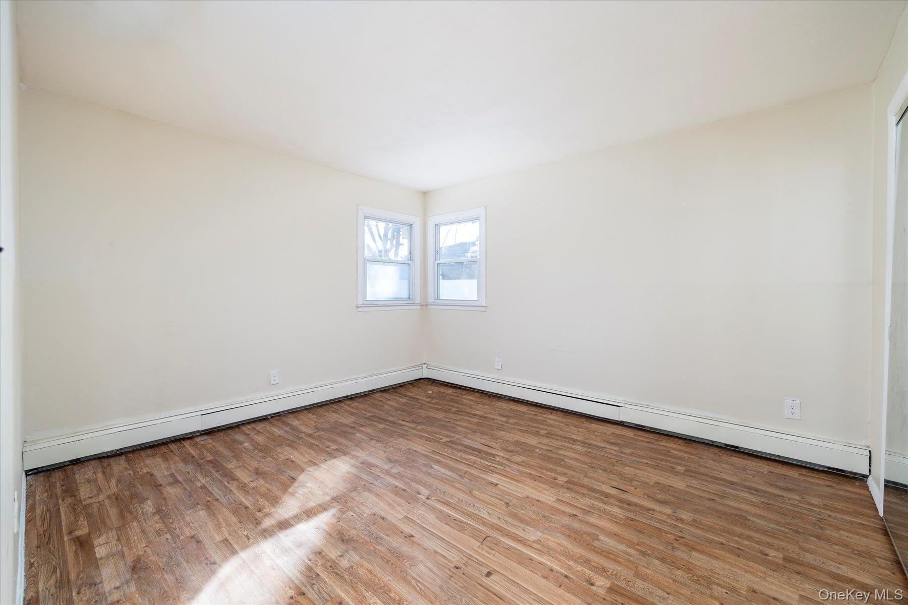143 Wellington Road Elmont, NY 11003 - Photo 16 of 24 an empty room with wooden floor and windows