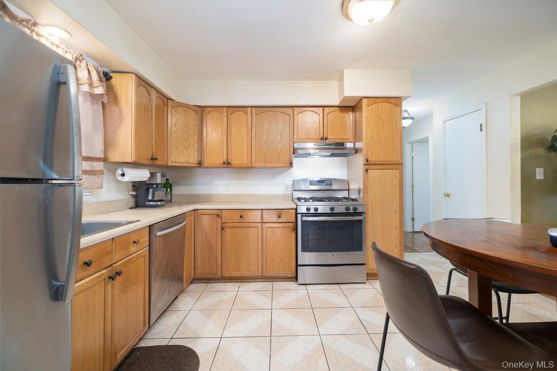 143 Wellington Road Elmont, NY 11003 - Photo 6 of 24 a kitchen with a stove a sink and a refrigerator