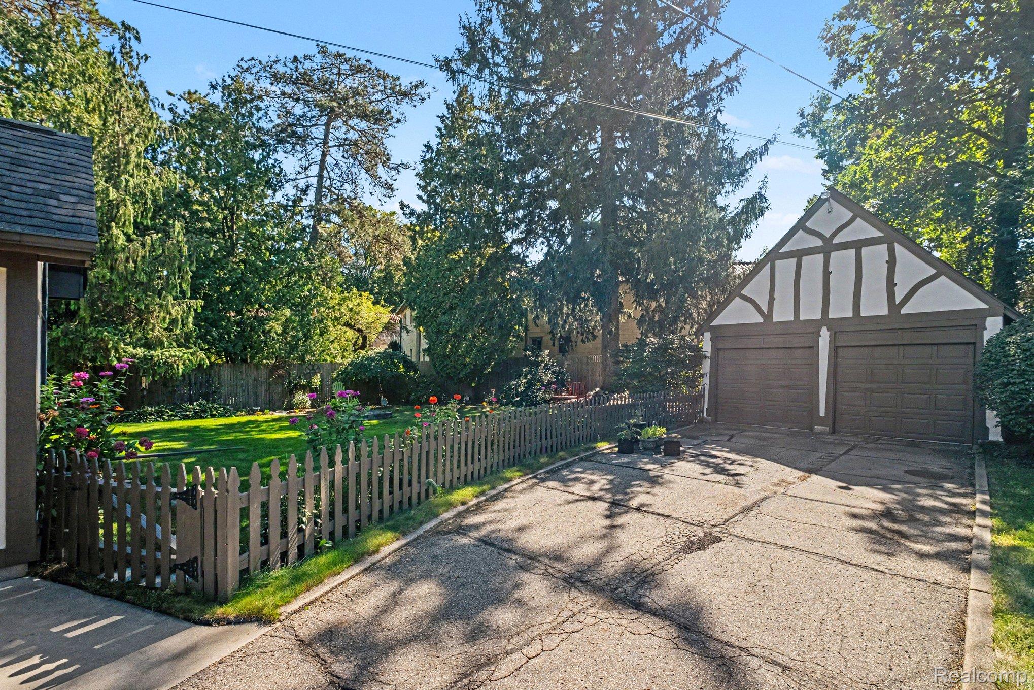 2030 Hampden Road Flint, MI 48503 - Photo 30 of 34 Tudor-style two-car garage with arched detailing, concrete driveway, and a gated picket fence enclosing a manicured lawn