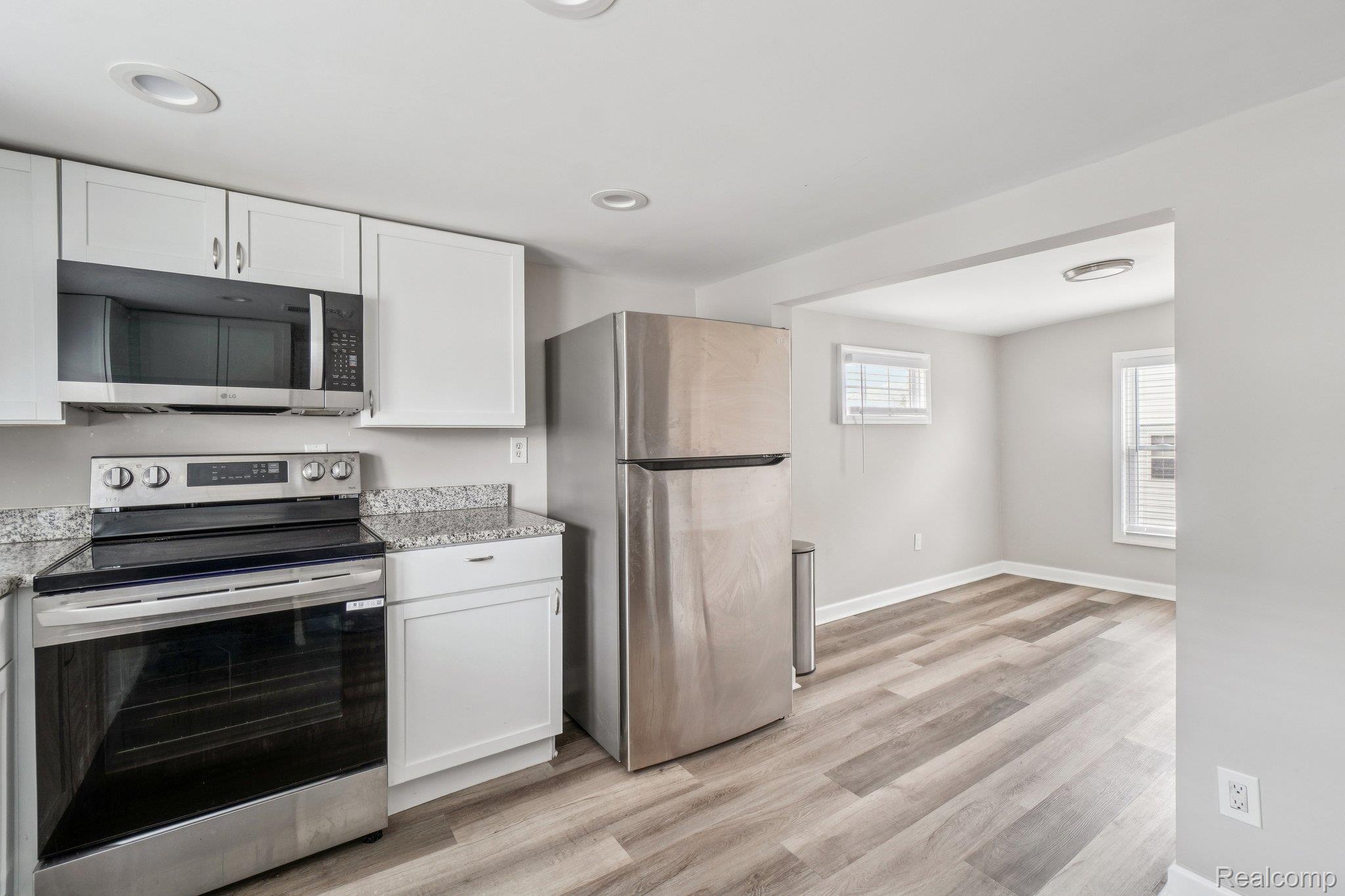 3822 Wabash Street Detroit, MI 48208 - Photo 10 of 17 Kitchen with stainless steel appliances, white cabinets, light wood-style flooring, light stone counters, and recessed lighting