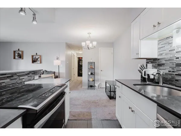 a kitchen with granite countertop a stove and a white cabinets