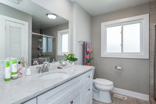 a bathroom with a granite countertop sink vanity mirror and toilet