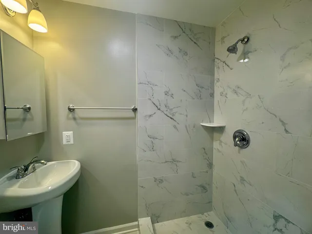 a bathroom with a sink shower and a mirror