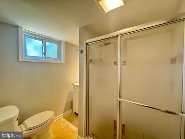a bathroom with a granite countertop toilet and a shower