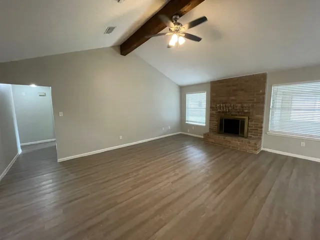 an empty room with wooden floor fan and window