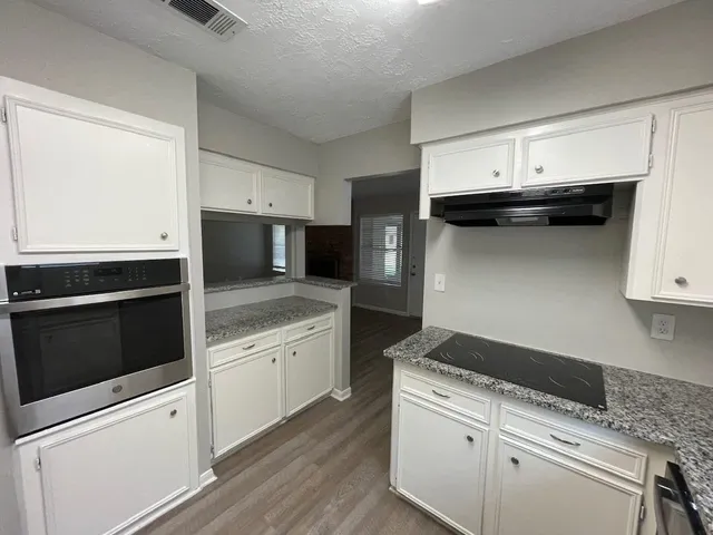 a kitchen with granite countertop white cabinets and black appliances