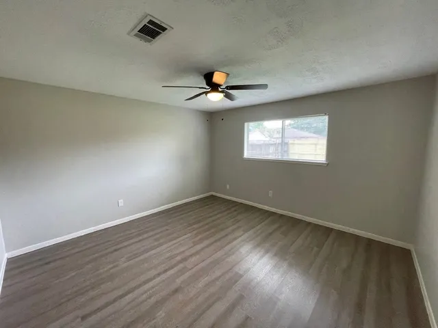 an empty room with wooden floor and ceiling fan