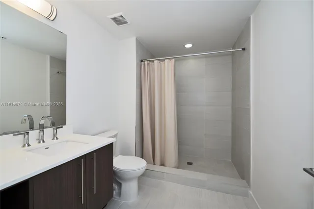 a bathroom with a shower sink vanity and toilet
