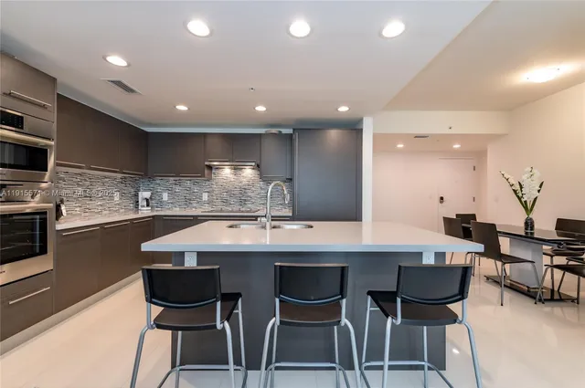 a kitchen with cabinets a sink dishwasher a dining table and chairs with wooden floor