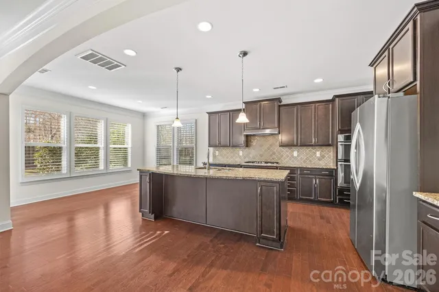 a large kitchen with granite countertop a large counter top appliances and cabinets
