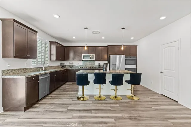 a kitchen with stainless steel appliances granite countertop a sink a stove and a refrigerator