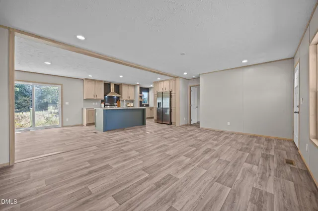a view of empty room with a kitchen and wooden floor
