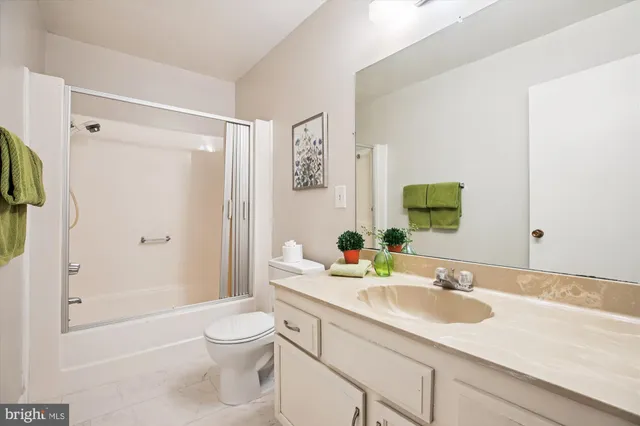 a bathroom with a granite countertop sink toilet a large mirror a shower and a bathtub