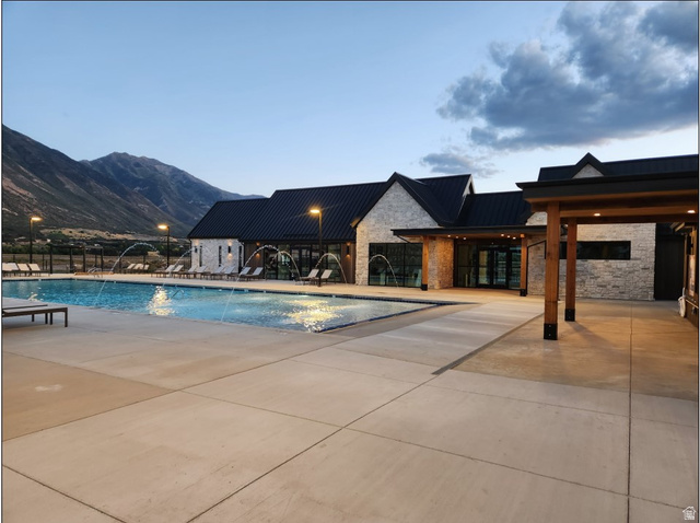2032 East Dorset Way, Unit 286 Salem, UT 84653 - Photo 19 of 23 Community swimming pool featuring a large concrete deck, water fountains, and a stone-clad clubhouse with black metal roofing