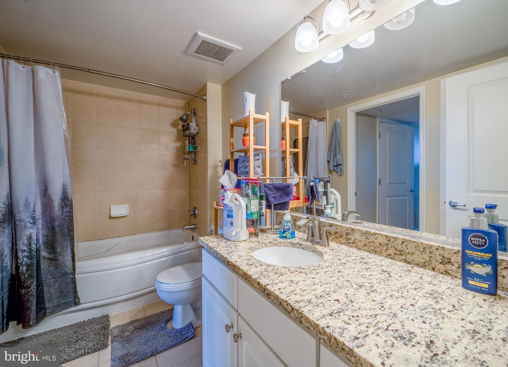 11800 Sunset Hills Road, Unit 925 Reston, VA 20190 - Photo 25 of 49 a bathroom with a granite countertop sink a toilet a mirror and shower