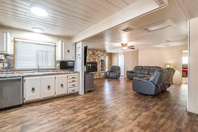 a large living room with stainless steel appliances granite countertop furniture and a wooden floor