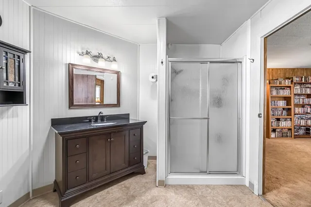 a bathroom with a granite countertop sink a mirror and shower
