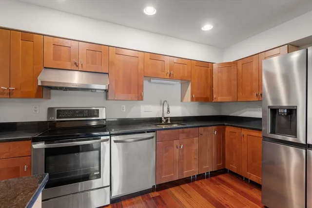 a kitchen with stainless steel appliances granite countertop a sink a stove and a refrigerator