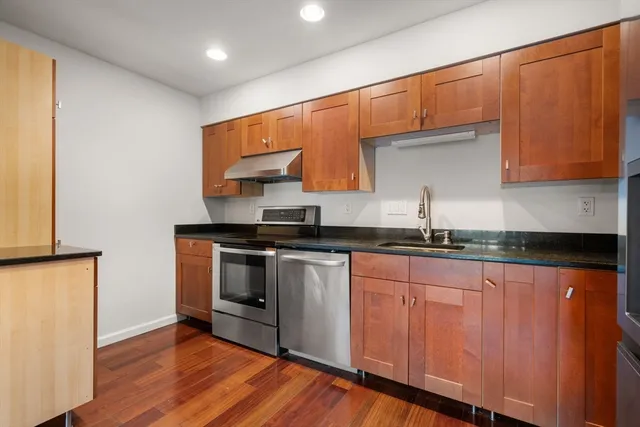 a kitchen with granite countertop a stove top oven and cabinets