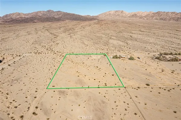 a view of a dry yard with wooden fence