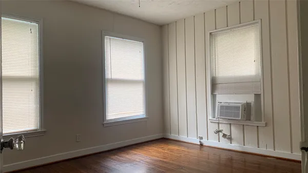 an empty room with wooden floor closet and windows