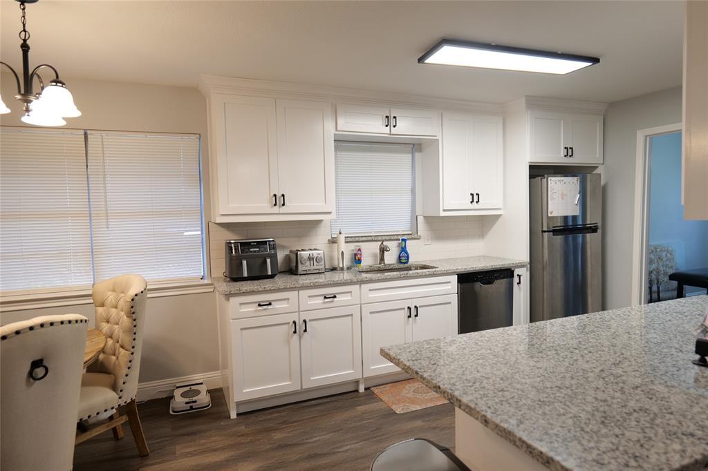 Kitchen featuring white cabinetry, light-toned countertops, a stainless steel refrigerator, and wood-finish flooring