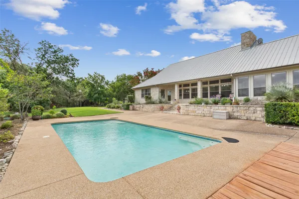 a view of a swimming pool with lawn chairs and plants