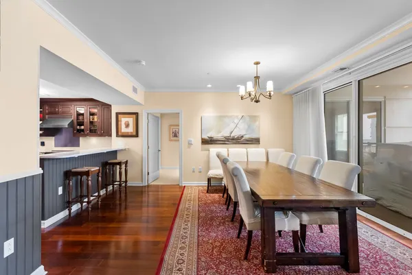 a dining room with wooden floor a chandelier a wooden table and chairs