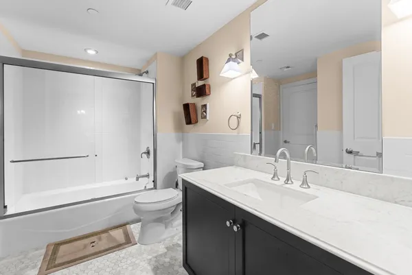 a bathroom with a sink a toilet and a large mirror