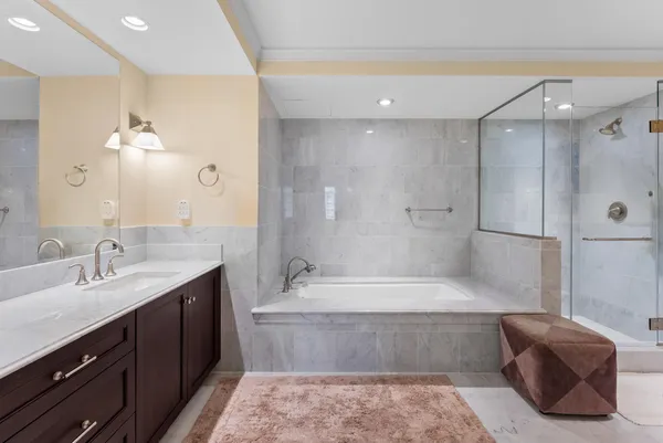 a bathroom with a tub a sink double vanity and a shower
