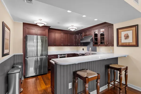 a kitchen with stainless steel appliances granite countertop a refrigerator a sink a stove and a microwave oven with wooden floor
