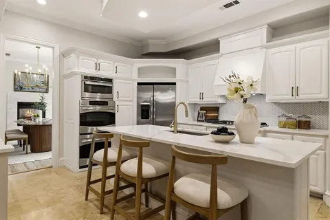 a kitchen with stainless steel appliances a sink a stove a table and chairs