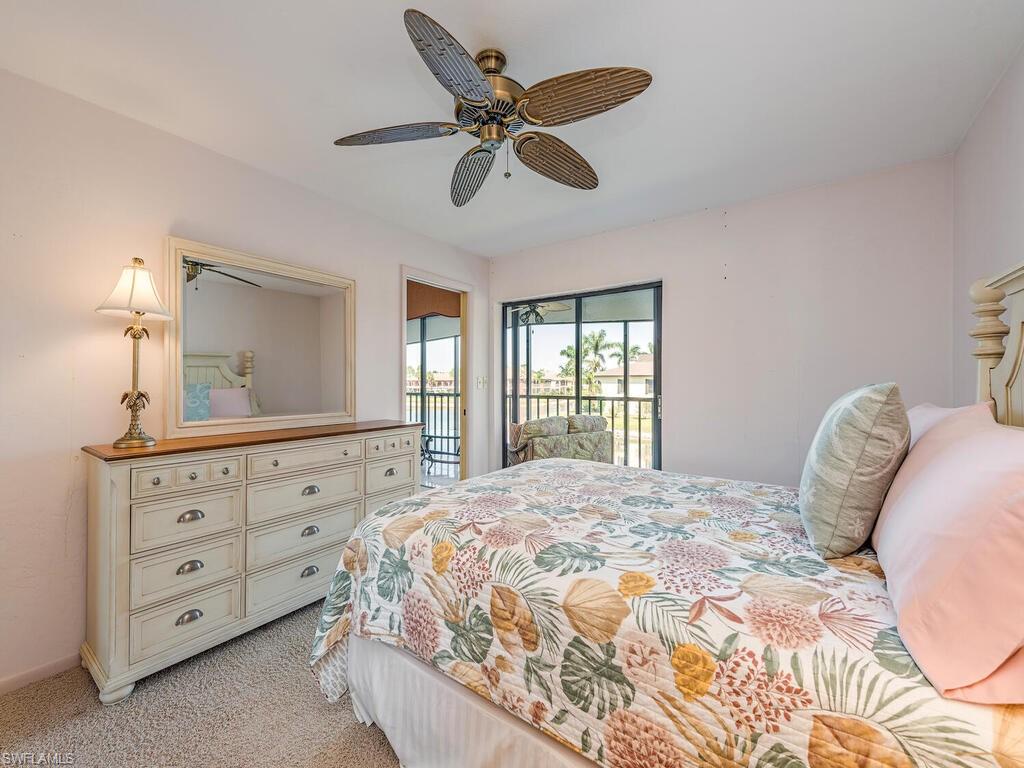 5590 Rattlesnake Hammock Road, Unit M203 Naples, FL 34113 - Photo 9 of 22 a bedroom with a bed a chandelier and a dresser