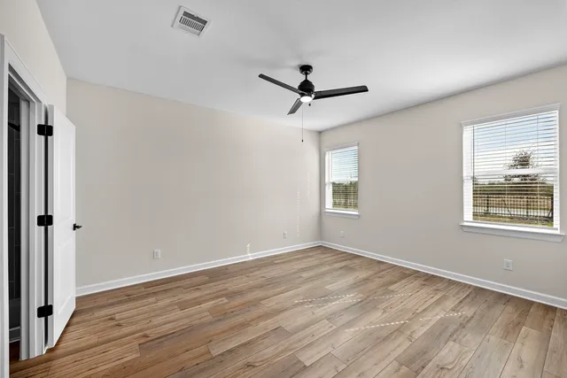 a view of empty room with wooden floor and fan
