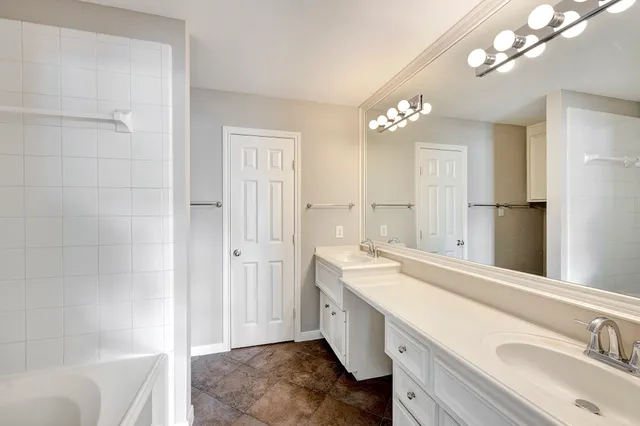 a bathroom with a sink a tub and a mirror