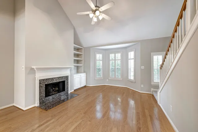 a view of an empty room with chandelier fan and fire place