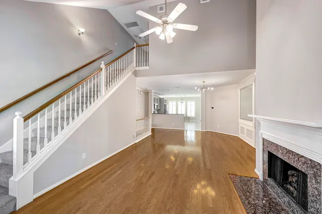a view of an empty room with wooden floor a ceiling fan and windows