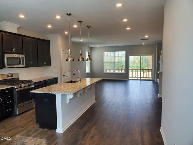 a large kitchen with stainless steel appliances granite countertop a sink a stove and a wooden floors