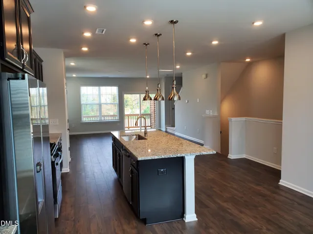 a kitchen with stainless steel appliances granite countertop a refrigerator a sink dishwasher and a refrigerator with wooden floor