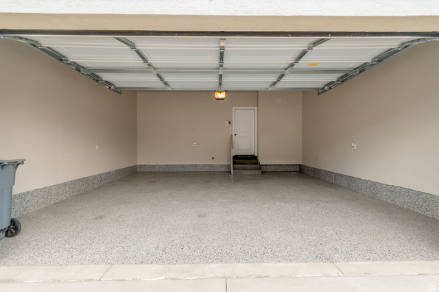 30 South Moonlit Road Mapleton, UT 84664 - Photo 23 of 25 Spacious garage featuring a finished epoxy floor, neutral painted walls, overhead lighting, and a white interior door with steps