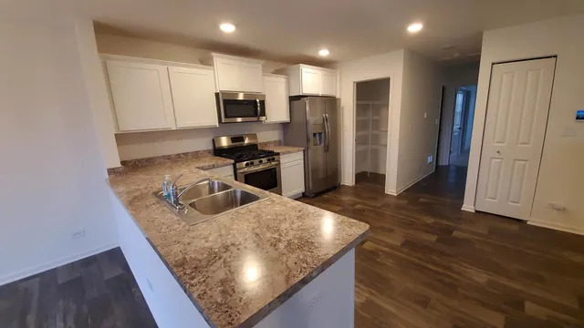 a kitchen with stainless steel appliances granite countertop a refrigerator stove top oven and sink