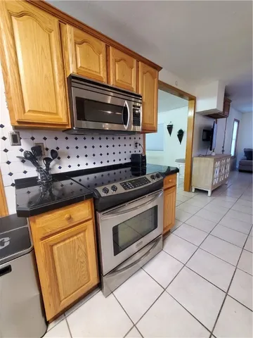 a kitchen with granite countertop a stove top oven microwave and cabinets