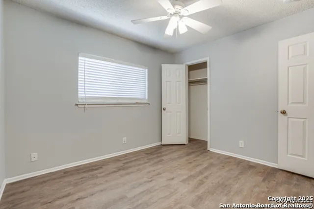 an empty room with wooden floor closet and windows