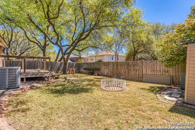 a view of backyard with wooden fence and a large tree