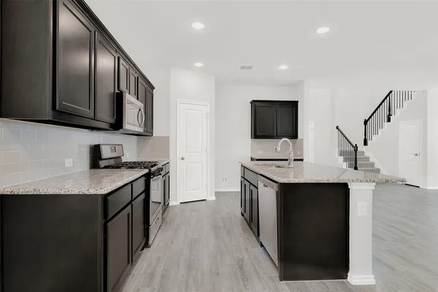 a view of kitchen with microwave a stove and a wooden floor