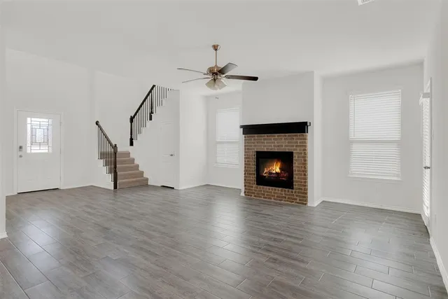 a view of a livingroom with a fireplace a ceiling fan and hardwood floor