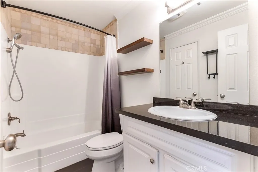 7890 East Spring Street, Unit 18F Long Beach, CA 90802 - Photo 10 of 31 a bathroom with a granite countertop sink a toilet a mirror and shower