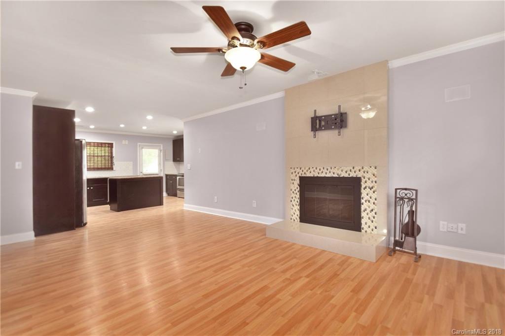 6426 Round Hill Road Charlotte, NC 28211 - Photo 5 of 23 a view of a livingroom with a fireplace a ceiling fan and kitchen view