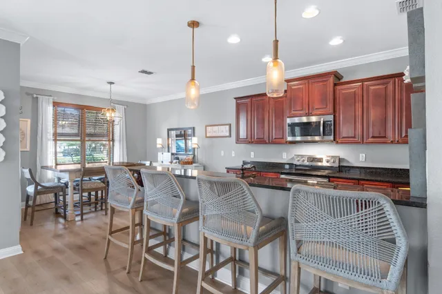 a kitchen with stainless steel appliances granite countertop a stove a sink a dining table chairs and view living room