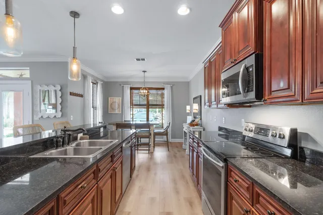 a kitchen with stainless steel appliances granite countertop a sink a stove top oven a chimney cabinets and couches